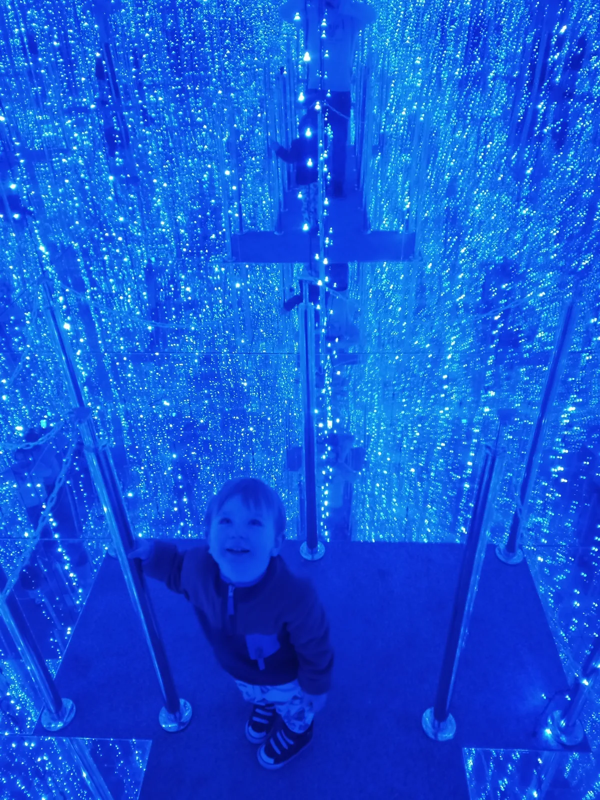 Child inside a blue infinity mirror room at Mirage Museum of Illusions in Sopot