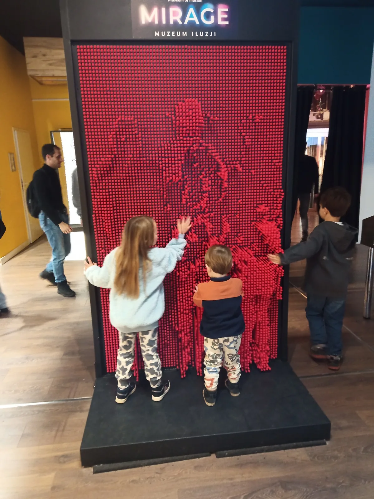 Children playing with the red pin wall at Mirage Museum of Illusions in Sopot